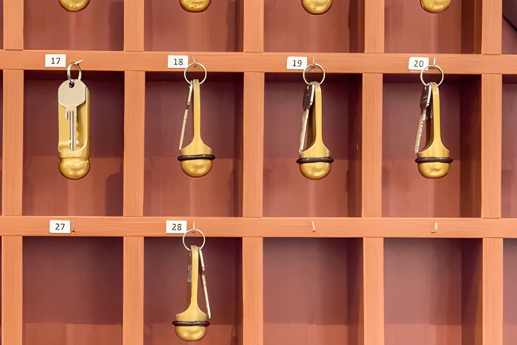 Klassische Hotelschlüssel mit goldenen Schlüsselanhängern in einem hölzernen Schlüsselregal – Professionelle Nachfertigung für Hotels und Industrie bei Meisterwerk Langenfeld.