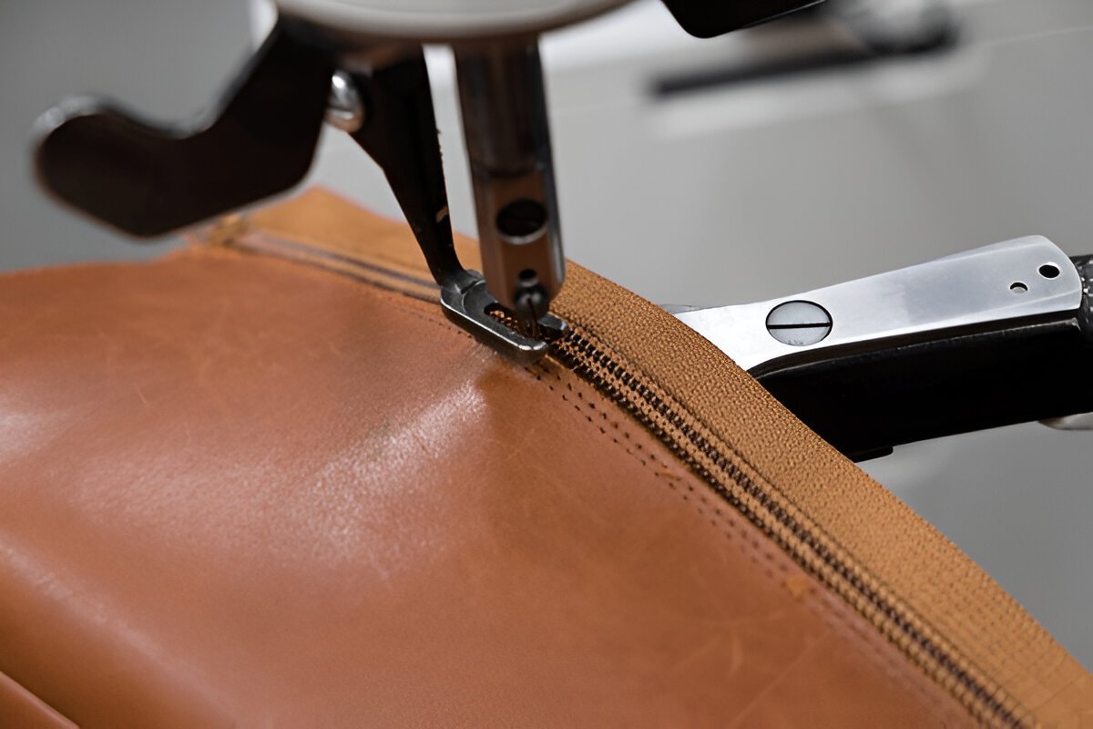 Schuhreparatur Langenfeld: Spezialnähmaschine ersetzt einen defekten Reißverschluss an einem braunen Lederstiefel.