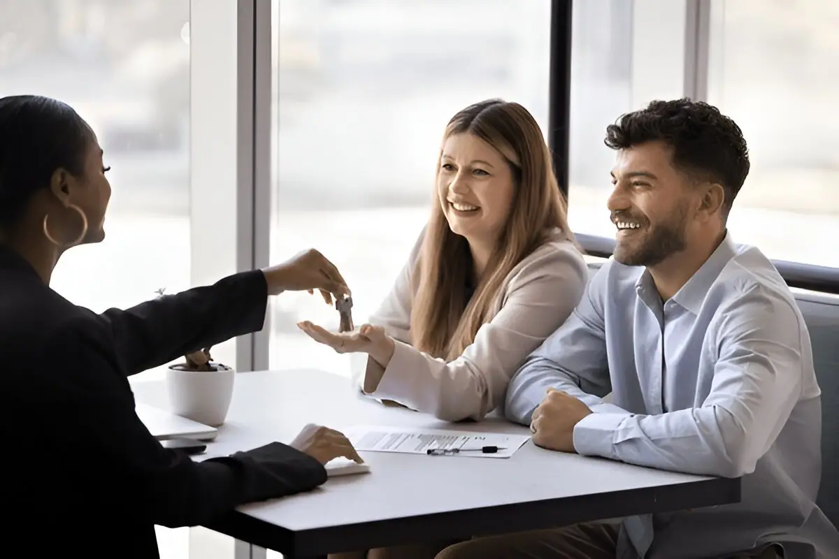 Professionelle Schlüsselübergabe in Langenfeld: Eine Beraterin übergibt einem glücklichen Paar die Schlüssel für ihr neues Objekt im Rahmen der Hausverwaltung.