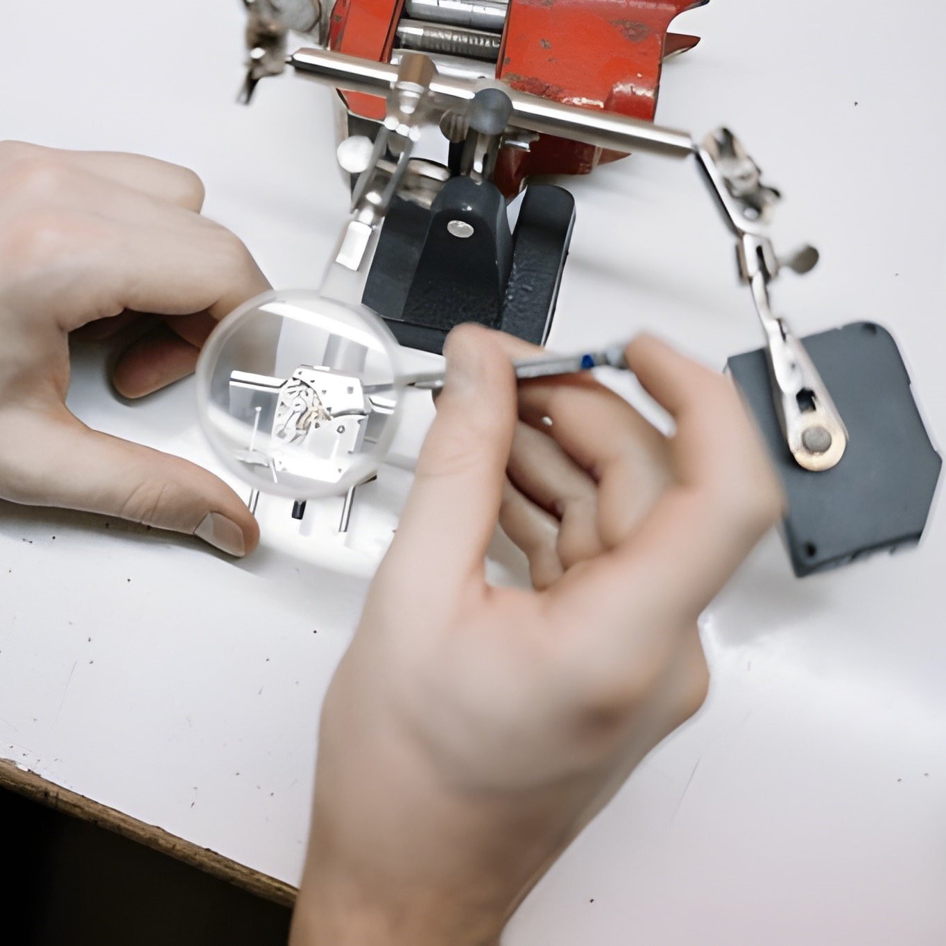 Uhrenservice Langenfeld: Ein Uhrmacher bei der präzisen Arbeit an einem Uhrwerk unter einer Lupe – Fachgerechter Austausch von Uhrengläsern und mechanische Wartung.